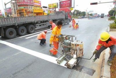 工人在用手推熱熔劃線機施劃標(biāo)線