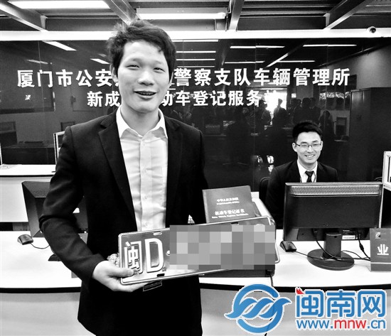 一名買(mǎi)車(chē)的顧客在4S店領(lǐng)取新車(chē)牌證