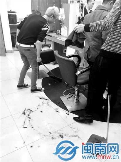 美發(fā)店工作人員將客人剪掉的碎頭發(fā)掃起來