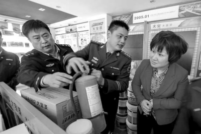 消防人員正在檢查一商鋪內(nèi)的消防器材