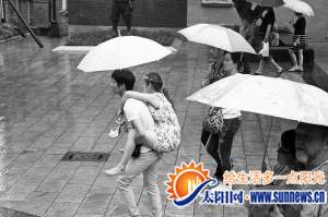 昨日下午，一名男子背著一名女子在雨中行走。