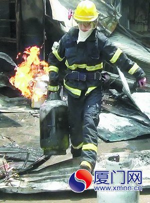 消防員從起火的小吃店內(nèi)搶出液化氣罐。