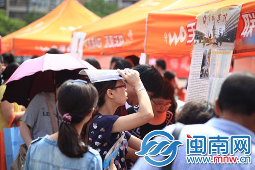 海都咨詢會現(xiàn)場，一名家長頂著烈日看學校信息