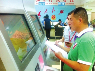 工作人員指導李建才在終端機上填寫材料。