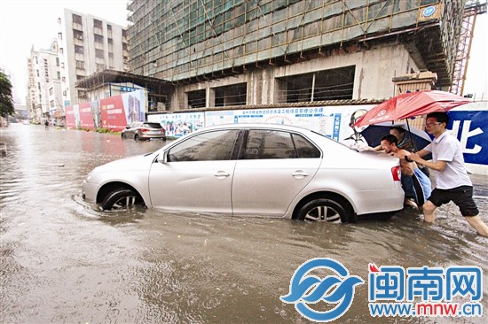眾人幫忙把熄火的小轎車推上拖車
